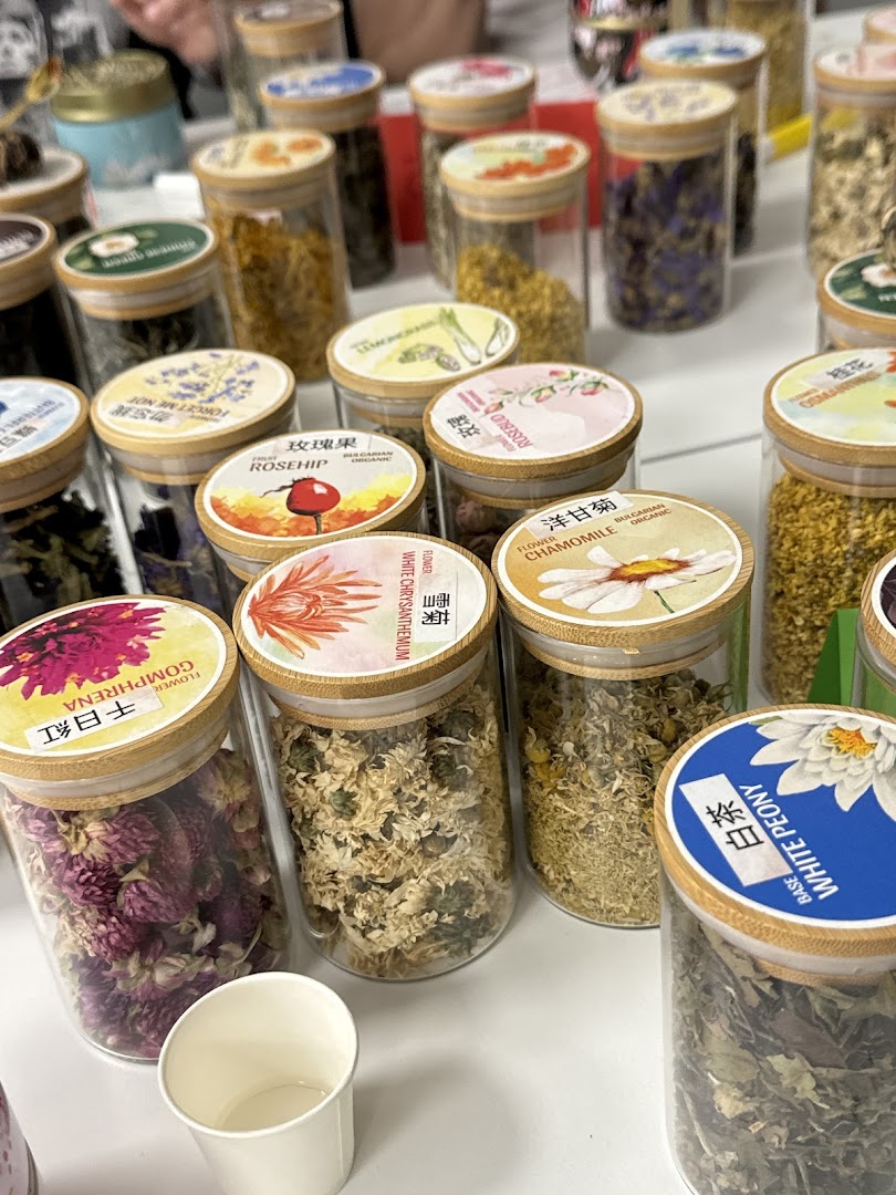 Close-up of various glass jars filled with dried flowers and herbs for tea.