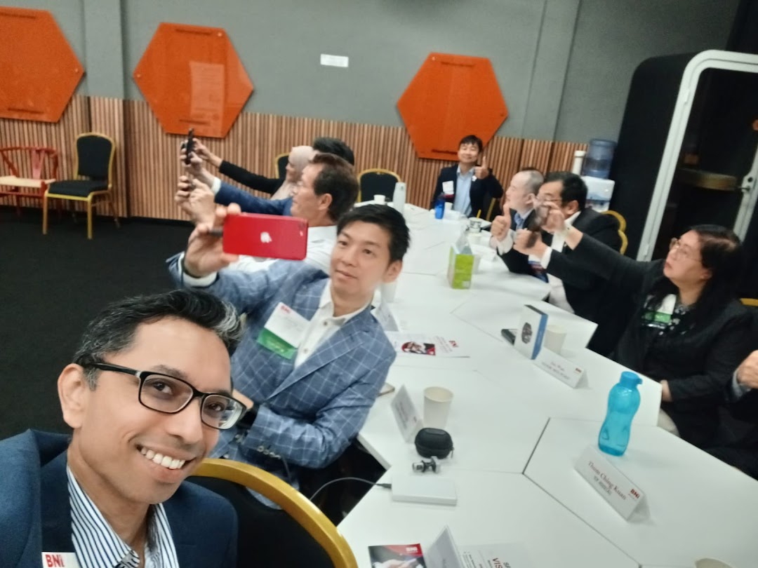 A group of business professionals actively participating in a meeting, with several individuals taking photos.