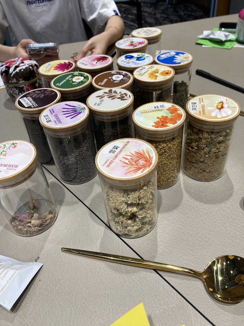 A collection of various dried tea ingredients and flowers displayed in clear glass jars.