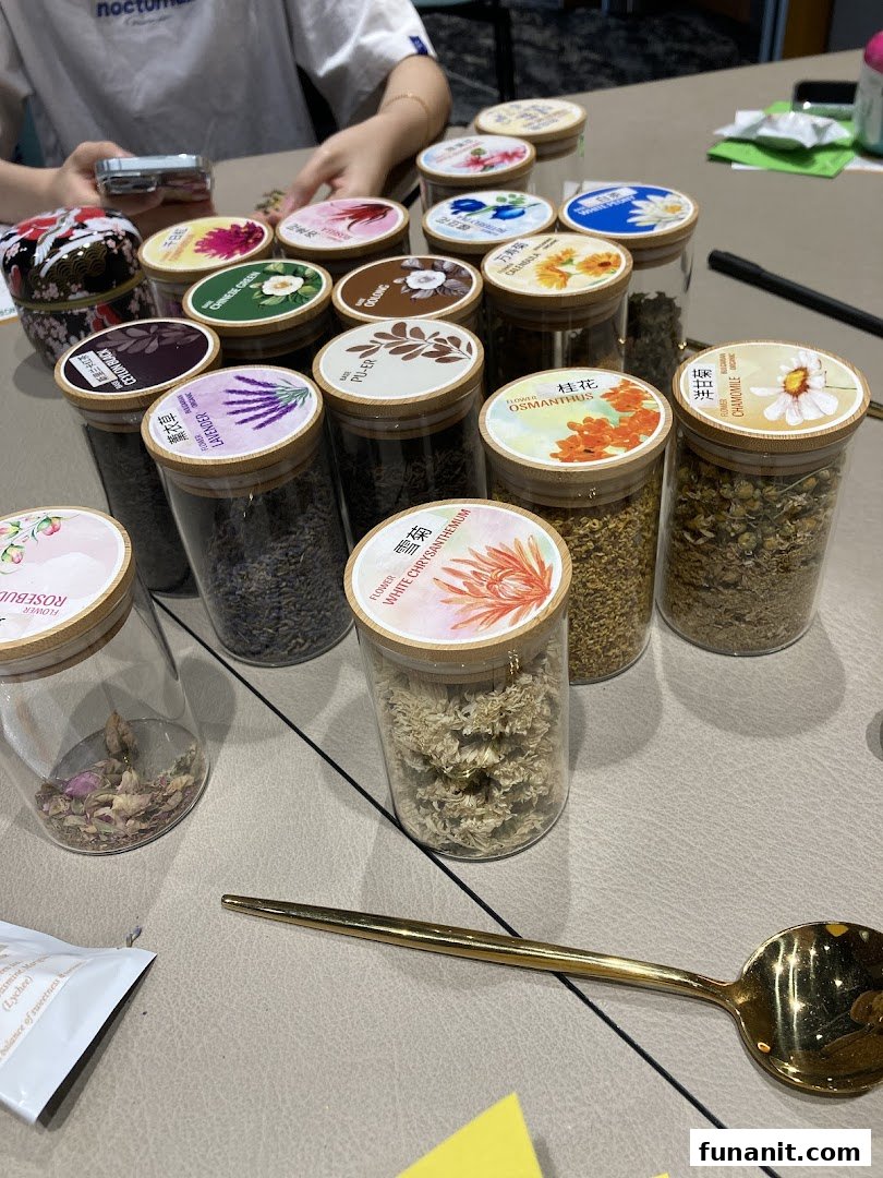 A collection of various dried tea ingredients and flowers displayed in clear glass jars.