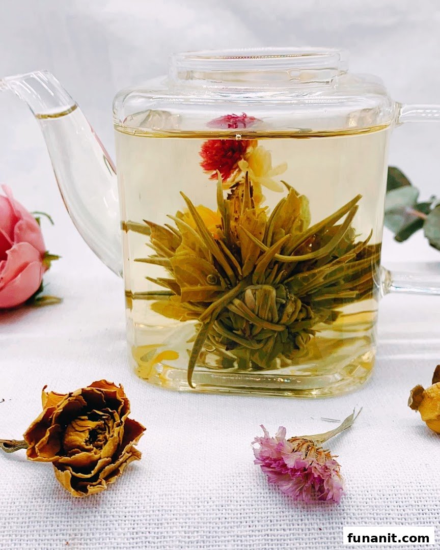 A clear glass teapot showcases a beautiful blooming tea flower unfurling in hot water.