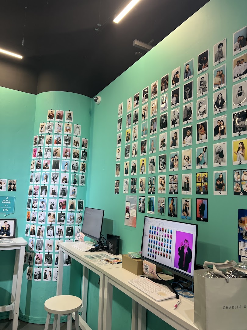 Interior of a self-photo studio with walls adorned by customer photos, desks, and computers.