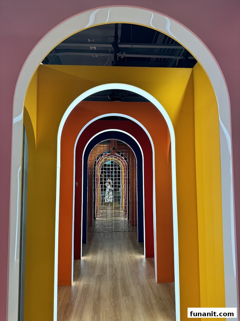 A vibrant, colorful arched hallway leading into a photo studio, with a person visible at the end.
