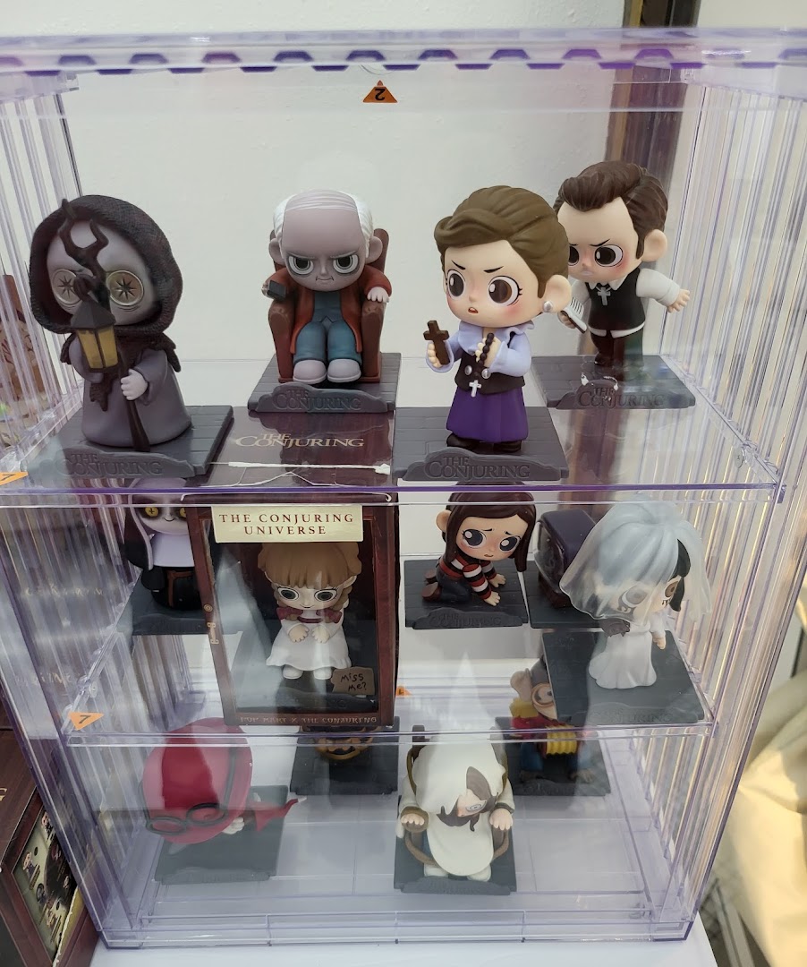 Collectible figures from The Conjuring Universe displayed in a clear POP MART showcase.