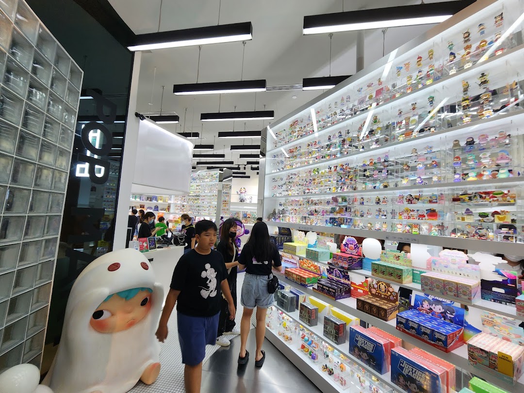 Inside POP MART, customers browse shelves filled with collectible art toys and blind boxes, featuring a large character statue.