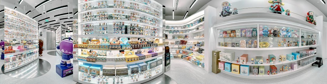 A brightly lit, modern retail store interior showcasing numerous collectible art toys and blind boxes on white shelves.