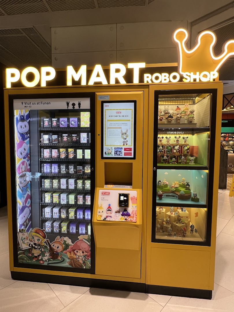 A vibrant yellow Pop Mart Robo Shop vending machine offering collectible blind boxes and displaying various figures.