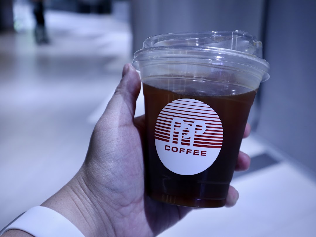 A hand holds a clear plastic cup of iced coffee featuring the distinctive PPP Coffee logo.