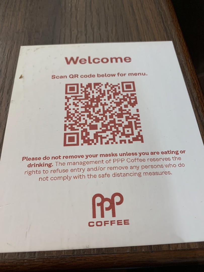 A sign at PPP Coffee displaying a QR code for the menu and mask-wearing guidelines.