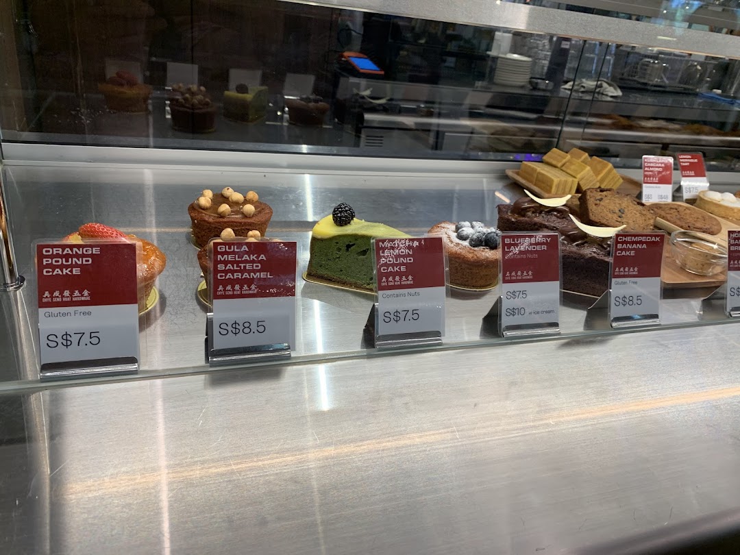 A vibrant display of freshly baked cakes and pastries with clear pricing in a glass showcase.