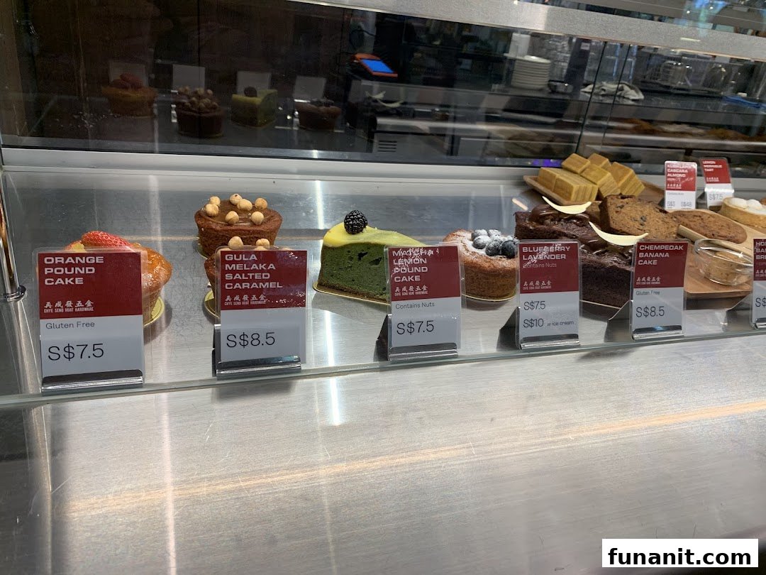 A vibrant display of freshly baked cakes and pastries with clear pricing in a glass showcase.