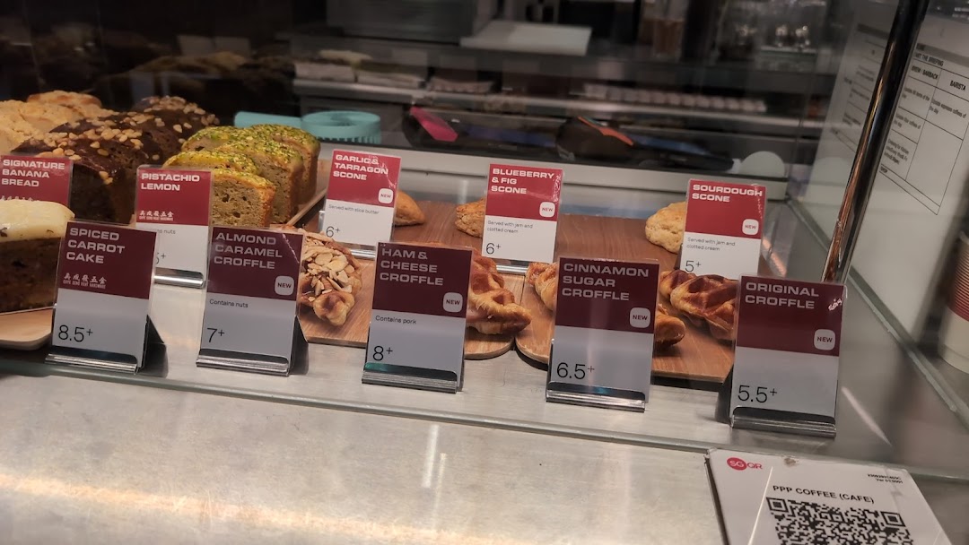 A display case showcasing a variety of freshly baked cakes, scones, and croffles with price tags.