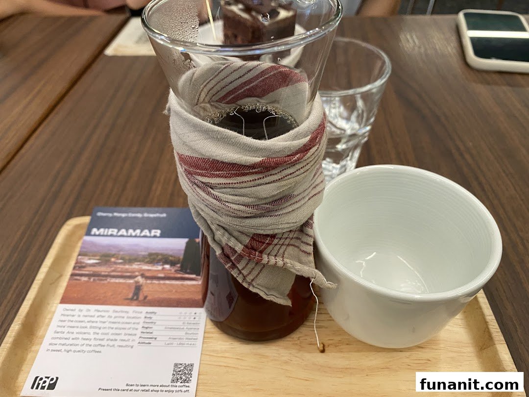 A pour-over coffee setup with a tasting card and cup on a wooden tray.