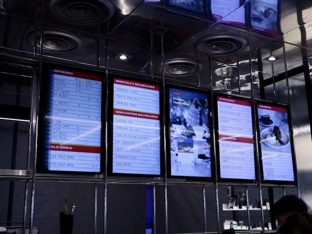 Digital menu boards at PPP Coffee displaying a wide range of coffee, beverages, food, and desserts.