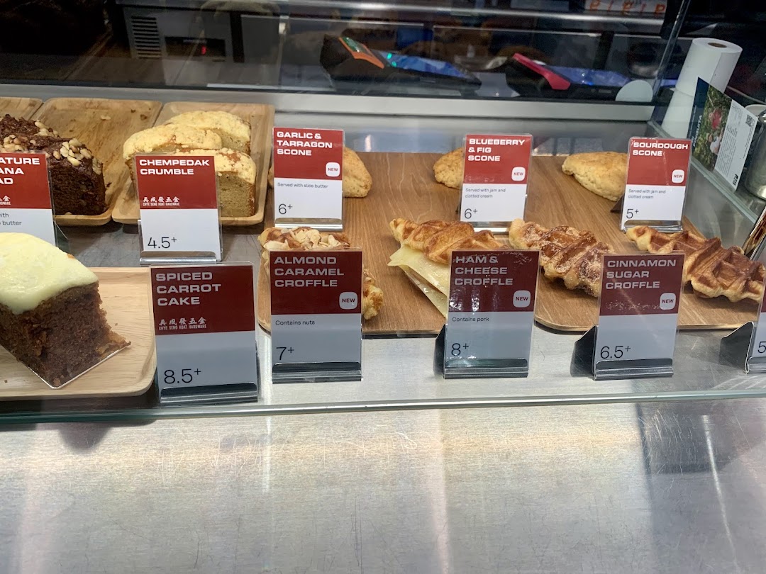 A display case showcasing a variety of freshly baked pastries, cakes, and croffles with price tags.