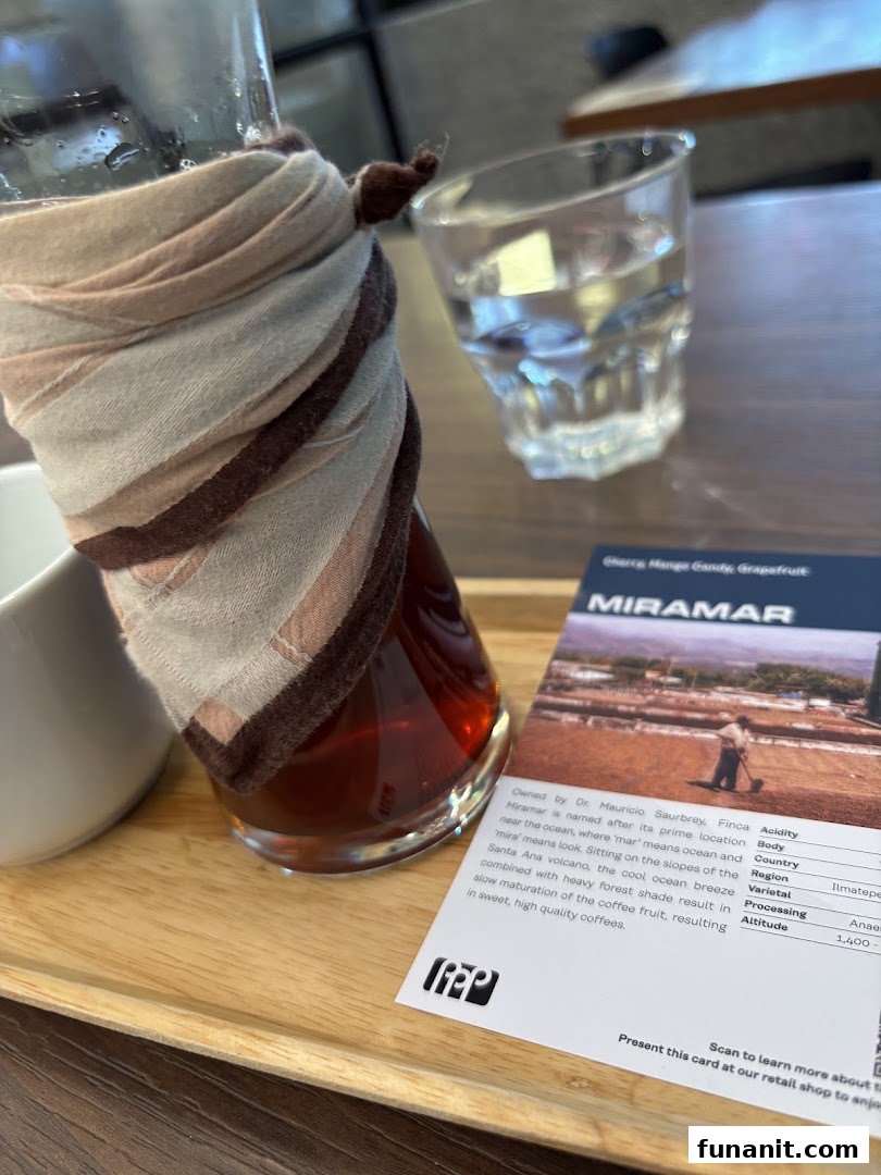 A coffee carafe, water glass, and coffee information card on a wooden tray.