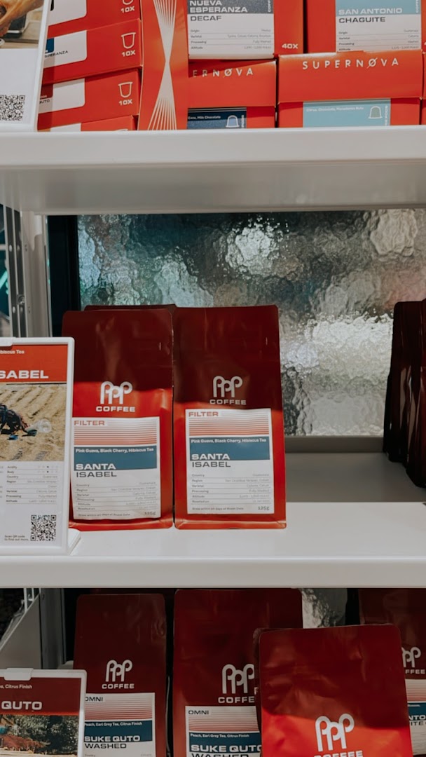 A display of various PPP Coffee products, including coffee beans and capsules, on shelves.