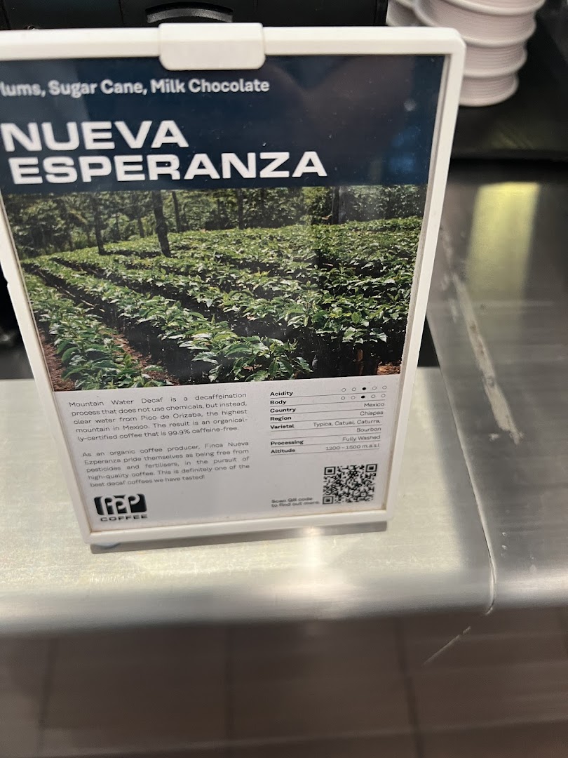 A display card at PPP Coffee detailing Nueva Esperanza decaf coffee beans with origin and flavor notes.