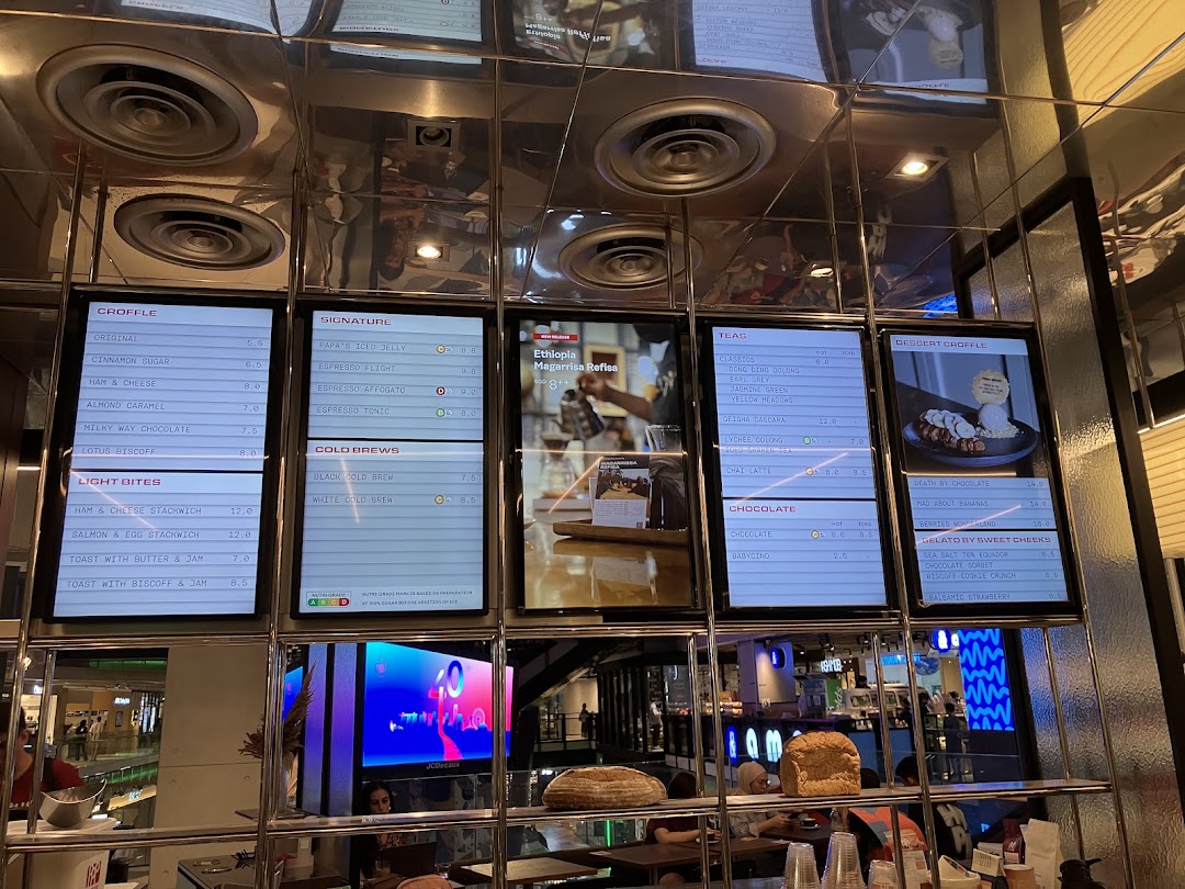 Digital menu boards at PPP Coffee displaying a variety of coffee, tea, croffles, and light bites.