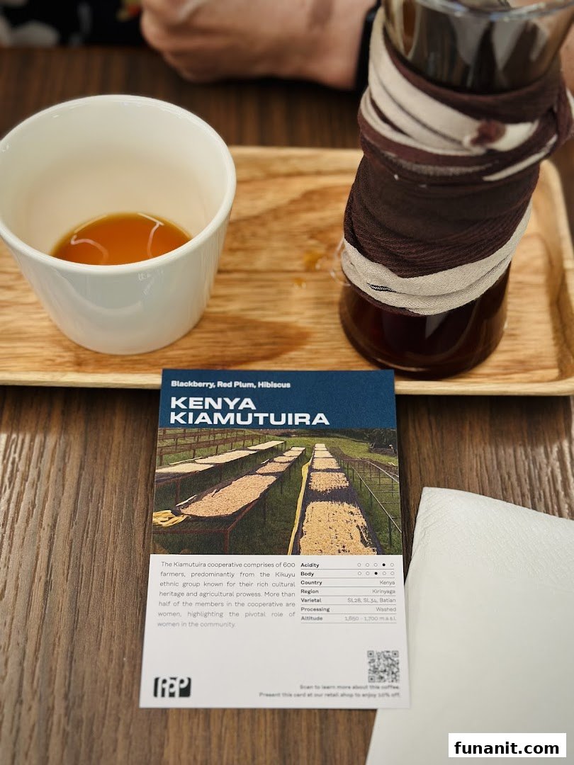 A close-up of a coffee cup, carafe, and a detailed card describing Kenya Kiamutuira coffee beans.