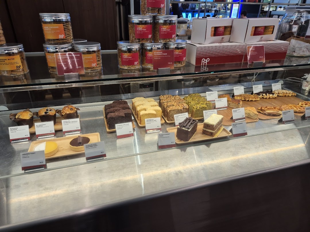 A display case showcasing a variety of freshly baked pastries, cakes, and packaged gourmet cookies at PPP Coffee.