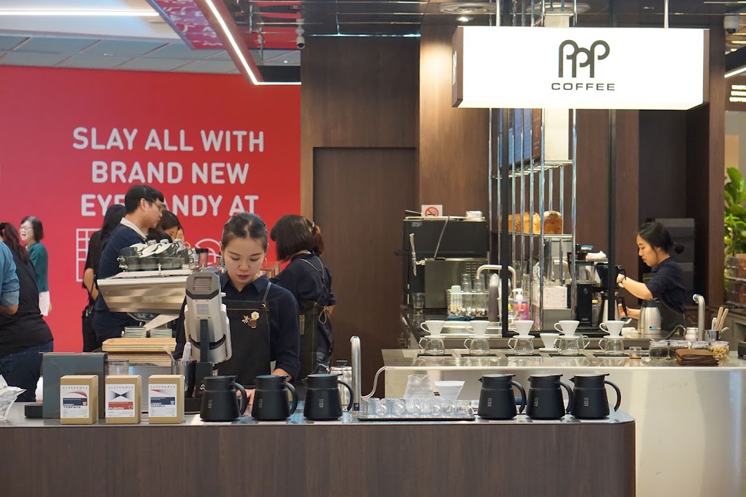 Baristas expertly prepare coffee at PPP Coffee's modern counter, showcasing brewing equipment and coffee products.