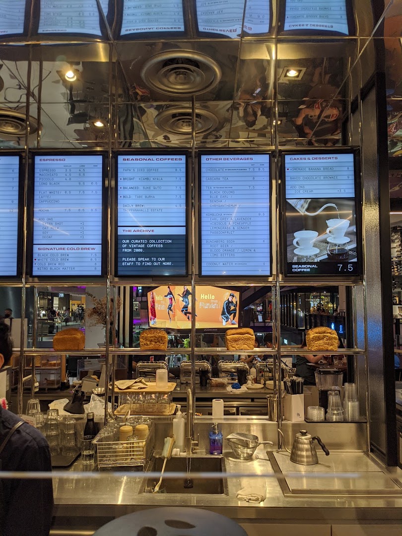 Digital menu boards displaying coffee, beverages, and desserts at PPP Coffee's counter.