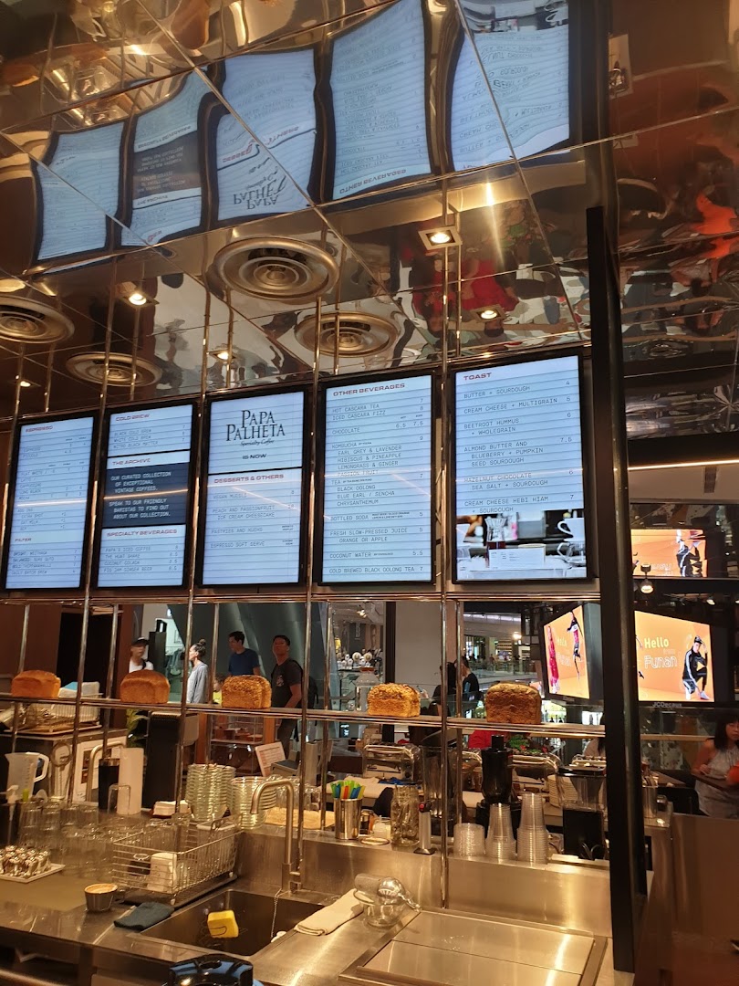 A coffee shop counter with digital menu boards displaying various coffee, beverage, and toast options.