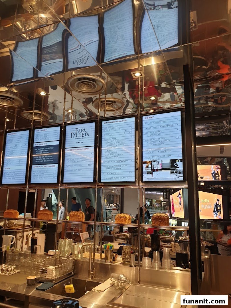 A coffee shop counter with digital menu boards displaying various coffee, beverage, and toast options.