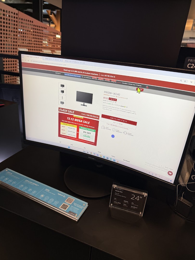 A PRISM+ monitor displaying a product page with flash sale details, alongside other tech accessories.