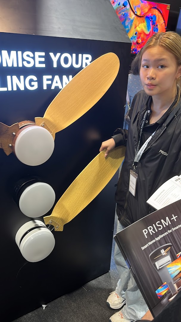 A person stands by a display showcasing PRISM+ smart home appliances and ceiling fans.
