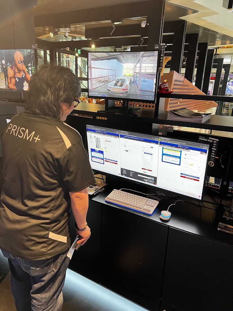 A person views multiple computer monitors displaying products and a video in a tech store.
