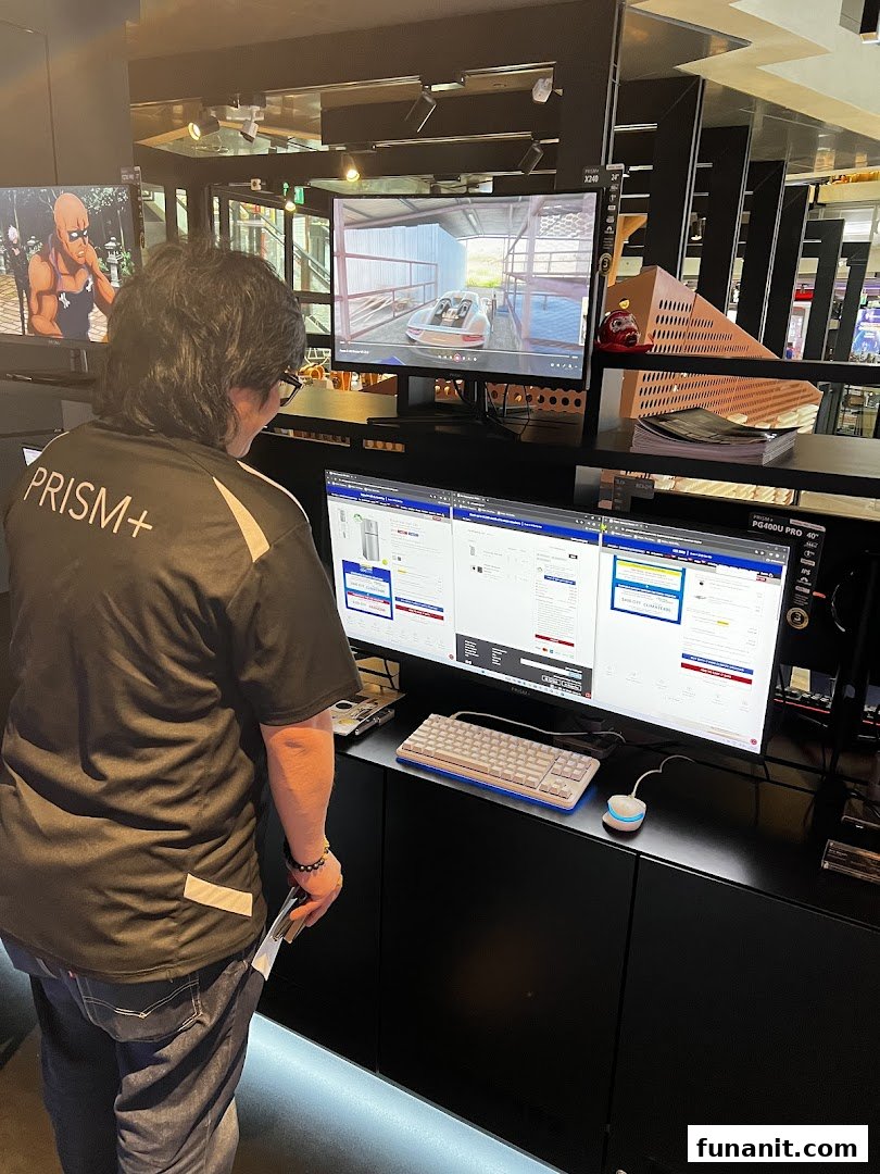 A person views multiple computer monitors displaying products and a video in a tech store.