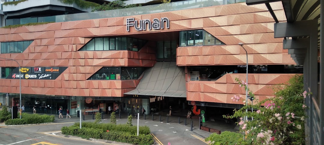 The distinctive brick-patterned exterior and main entrance of Funan shopping mall, featuring various tenant logos.