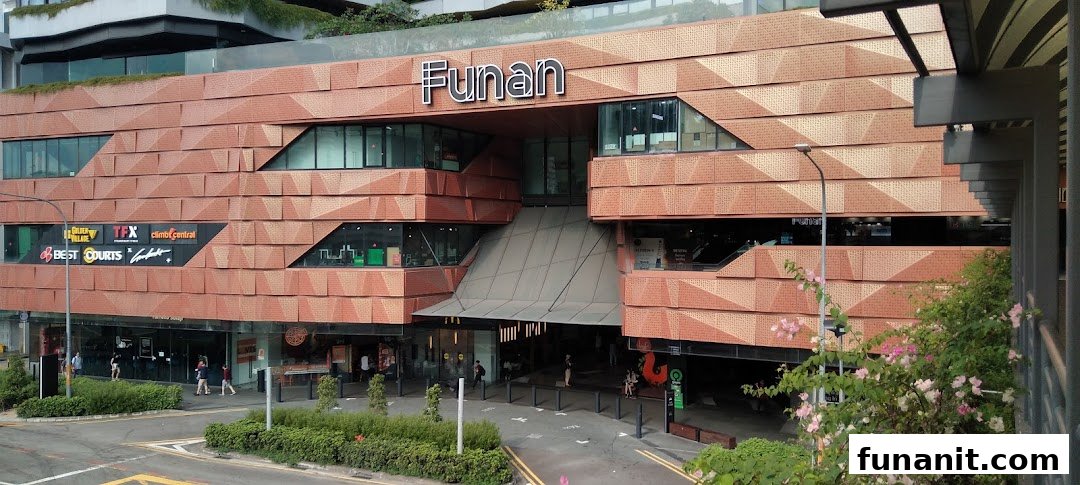 The distinctive brick-patterned exterior and main entrance of Funan shopping mall, featuring various tenant logos.