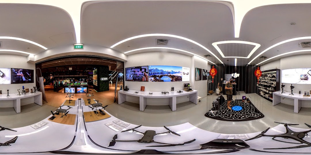 A wide-angle interior view of a modern electronics store featuring drones, cameras, and interactive displays.