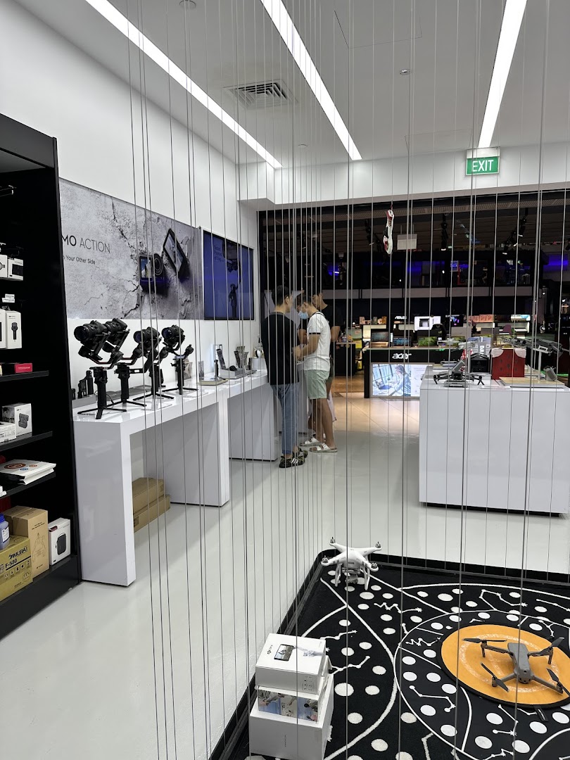 Interior view of an electronics store featuring cameras, drones, and customers browsing products.