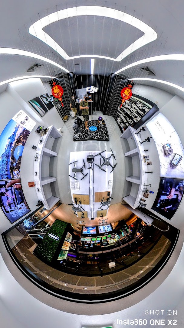 A wide-angle interior view of a modern tech store showcasing drones, cameras, and accessories on display.