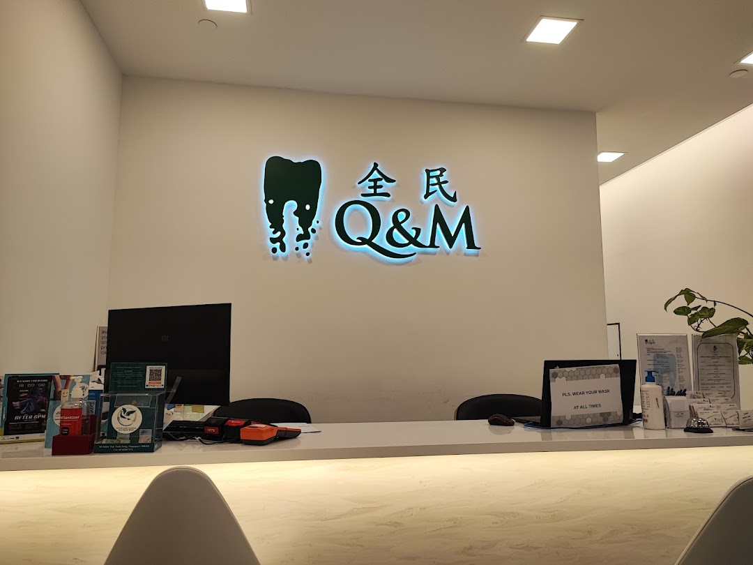 The brightly lit reception area of Q&M Dental Centre, featuring their prominent logo and a clean desk.