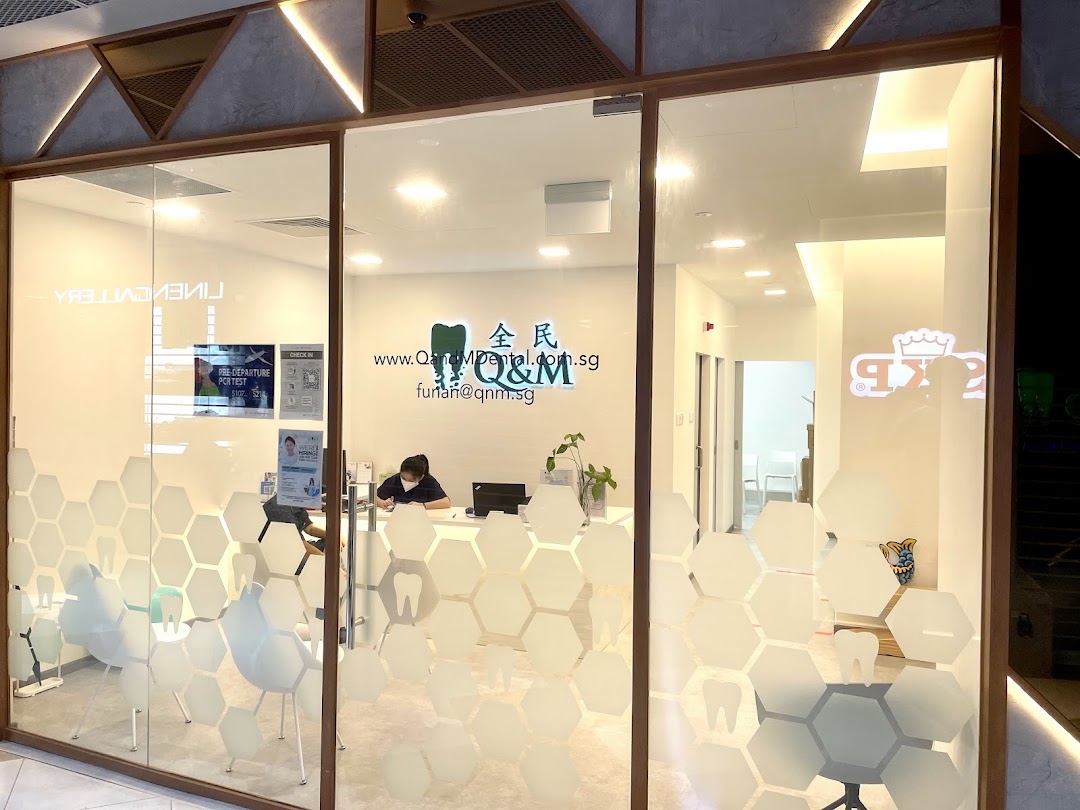The glass shop front of Q & M Dental Centre, showing the reception area and a staff member.