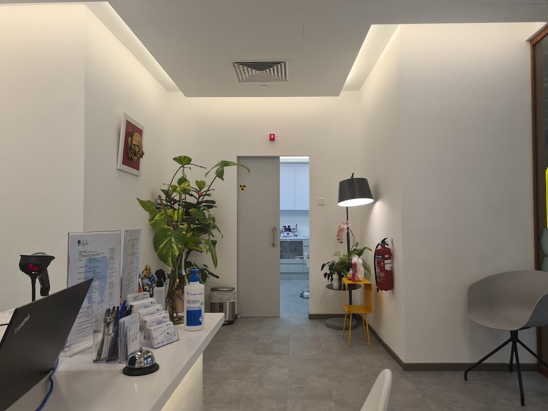 A clean and modern reception area of a dental clinic with a desk, plants, and seating.