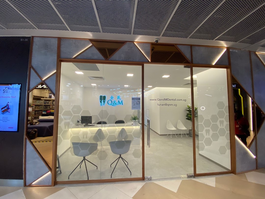 Modern shop front of Q&M Dental Centre with glass entrance and reception area visible.