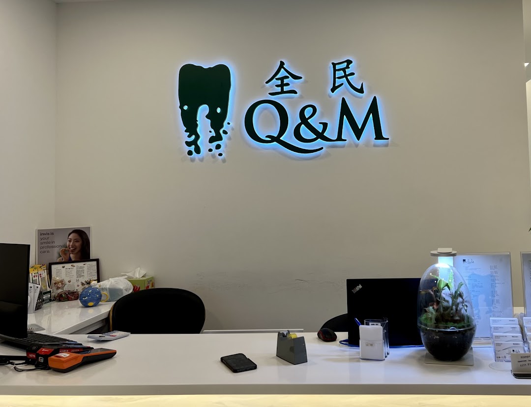 The reception area of Q&M Dental Centre with its illuminated logo and front desk.