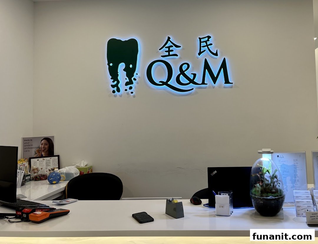 The reception area of Q&M Dental Centre with its illuminated logo and front desk.