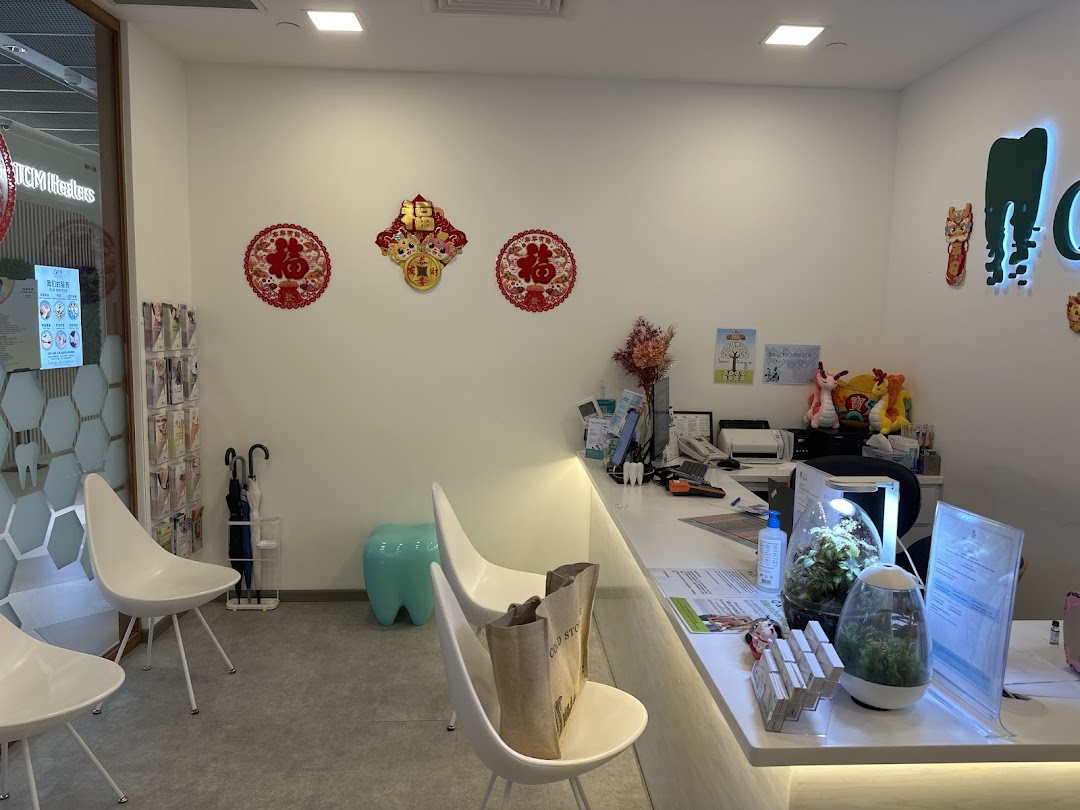 Modern dental clinic reception area with white counter, seating, and festive decorations.