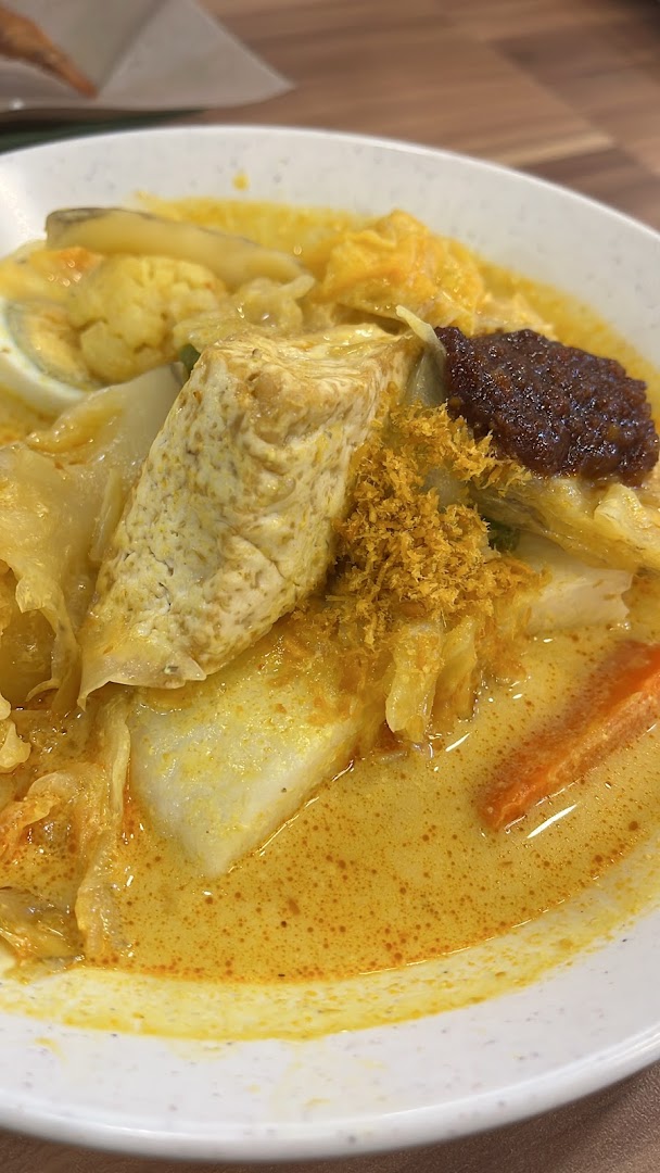 A vibrant bowl of Lontong with rich curry, tofu, egg, and spicy sambal from Qi Ji.