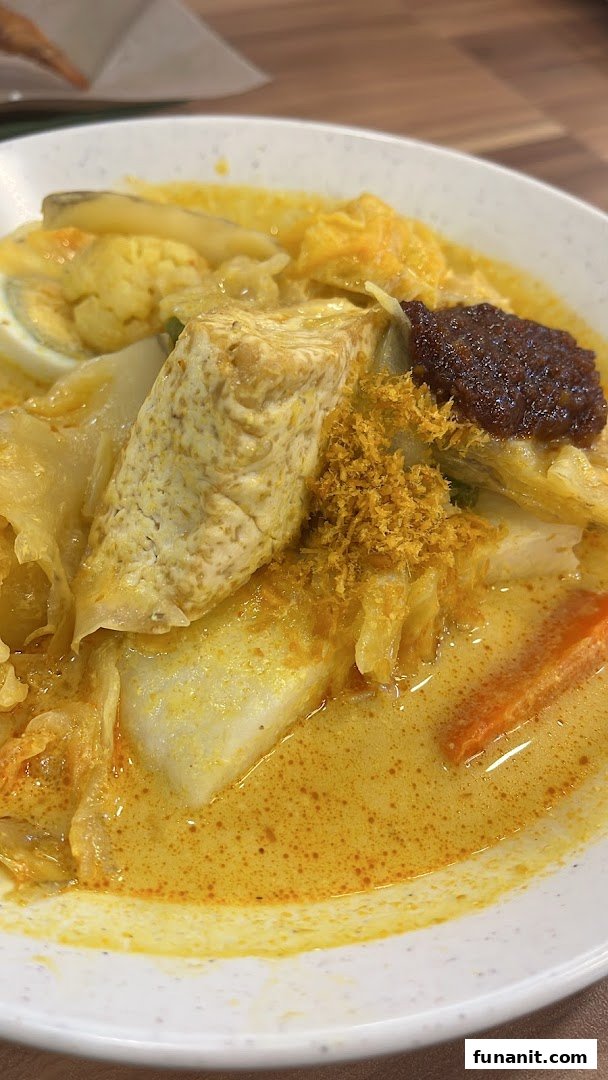 A vibrant bowl of Lontong with rich curry, tofu, egg, and spicy sambal from Qi Ji.