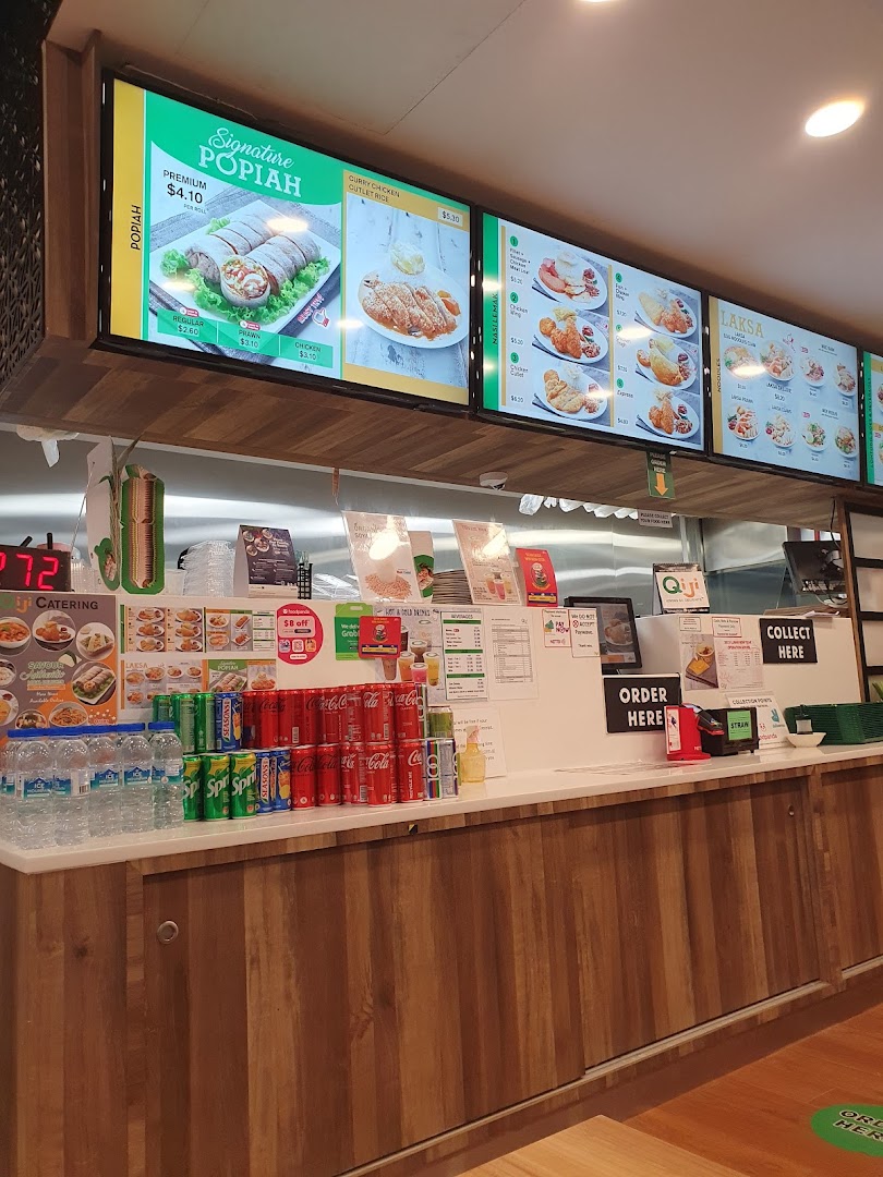 View of Qi Ji's food stall counter with digital menu boards showcasing Popiah, Laksa, and other local dishes.