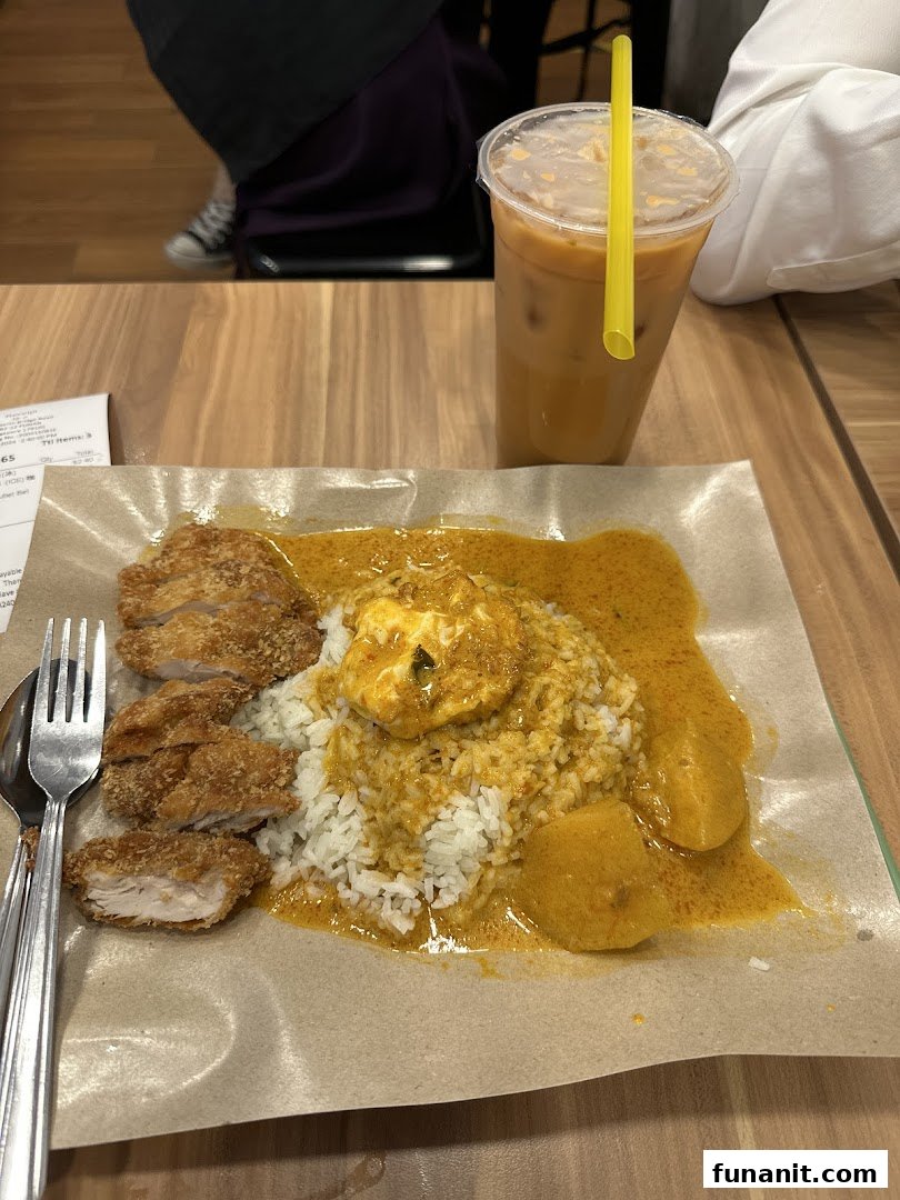 A delicious meal featuring rice, curry, fried chicken, and a refreshing drink on a wooden table.