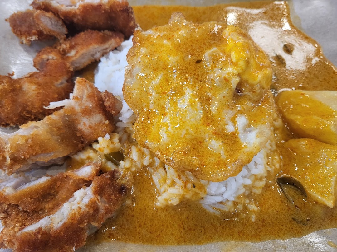 A close-up of delicious curry rice with crispy fried chicken cutlets and a sunny-side-up egg.